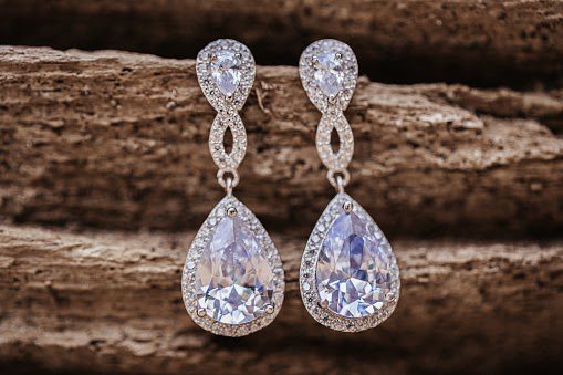 diamond wedding earrings hanging on wooden background, selective focus diamond wedding earrings hanging on wooden background, selective focus
